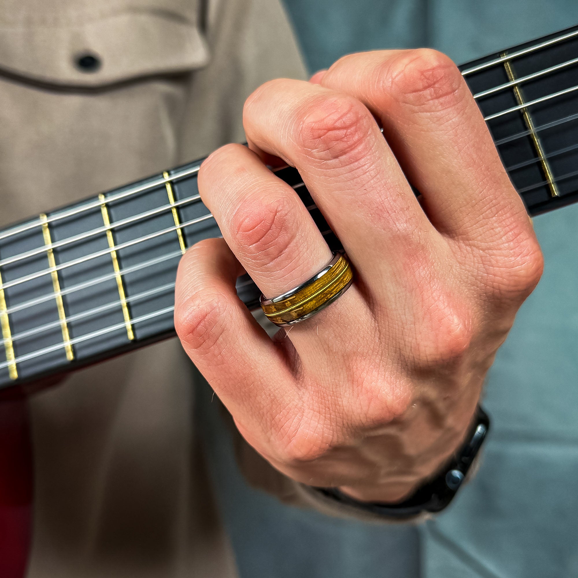 man wearing a tungsten ring with an inlay of recycled guitar wood and string
