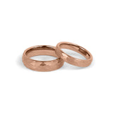 His and hers matching rose gold wedding rings with hammered surface displayed side by side