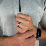 Close-up of a person wearing a silver ring on a gray background
