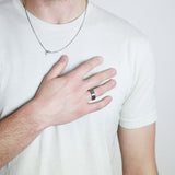 a man holding his hand against his chest wearing a unique wooden wedding ring