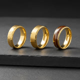 a row of gold tungsten rings photographed on a dark stone surface