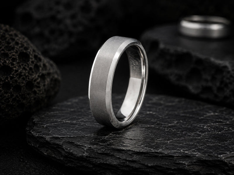 a collection of mens silver wedding rings photographed on a concrete surface