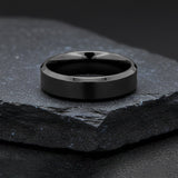 black titanium wedding band photographed on black slate