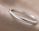 Ultra close-up macro photograph of a polished 2mm silver tungsten wedding ring showing smooth reflective metal detail and minimalist craftsmanship.
