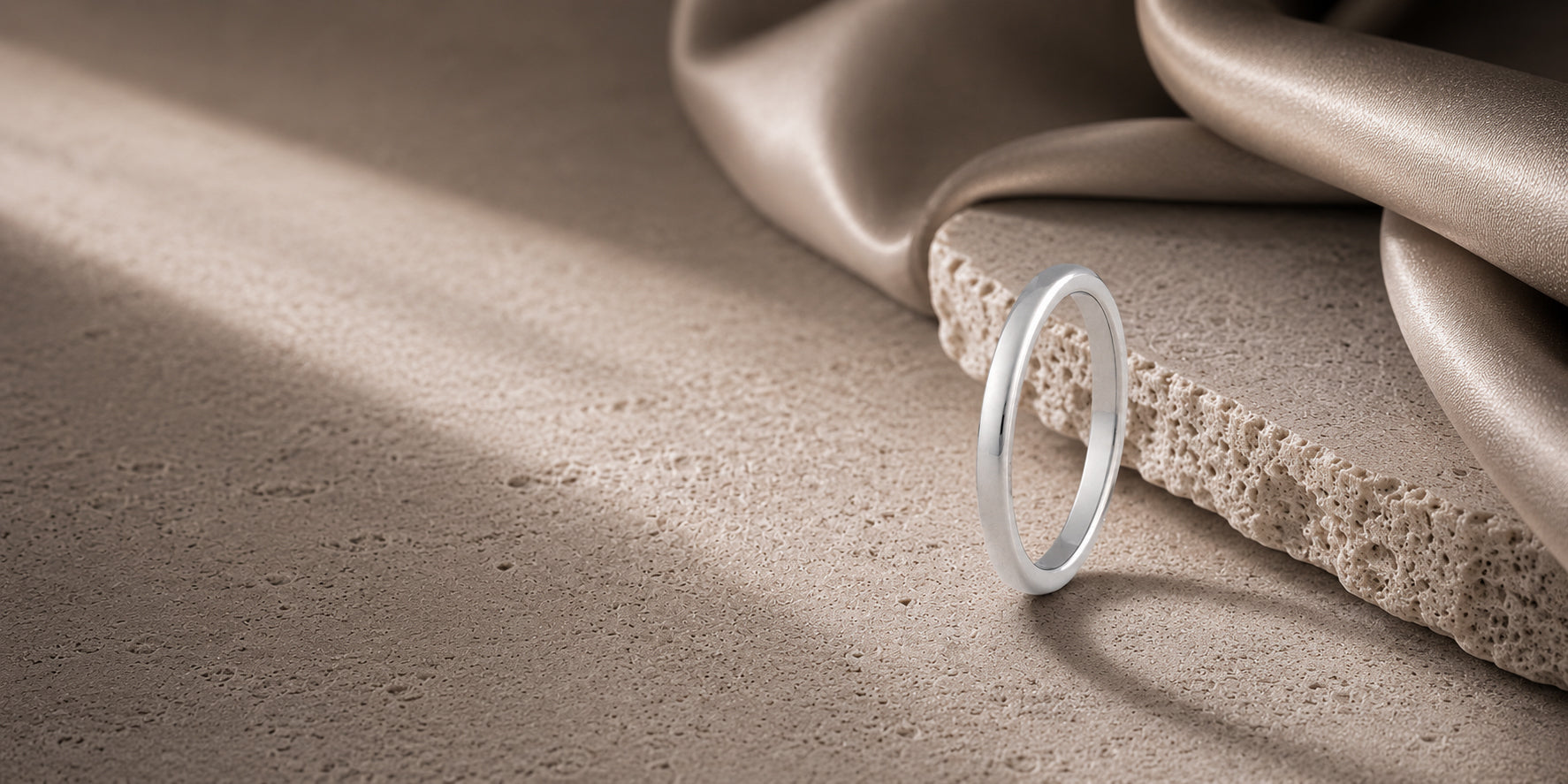 Minimalist 2mm silver tungsten wedding ring hero banner with soft stone textures and luxury neutral background for ecommerce collection page.