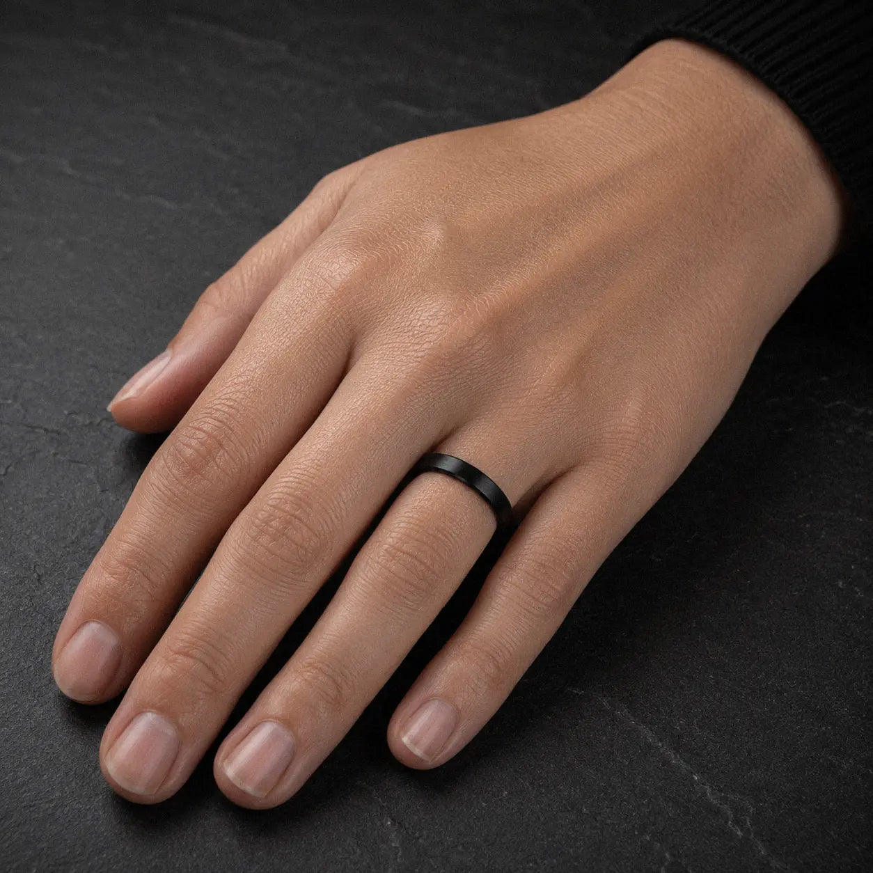 Woman wearing a 4mm brushed black tungsten wedding ring with a matte brushed finish.