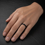 Woman wearing a 4mm brushed black tungsten wedding ring with a matte brushed finish.