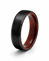 6mm brushed black tungsten wedding ring with polished edges and genuine whiskey wood sleeve shown at an angled view on a white background.