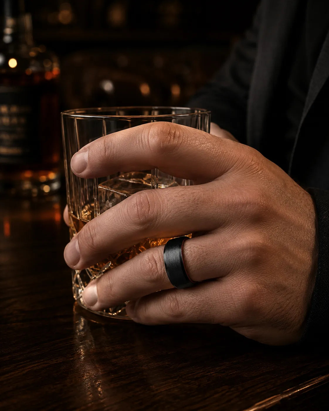 Man wearing an 8mm brushed black tungsten wedding ring with polished edges and maple wood sleeve while holding a whiskey glass