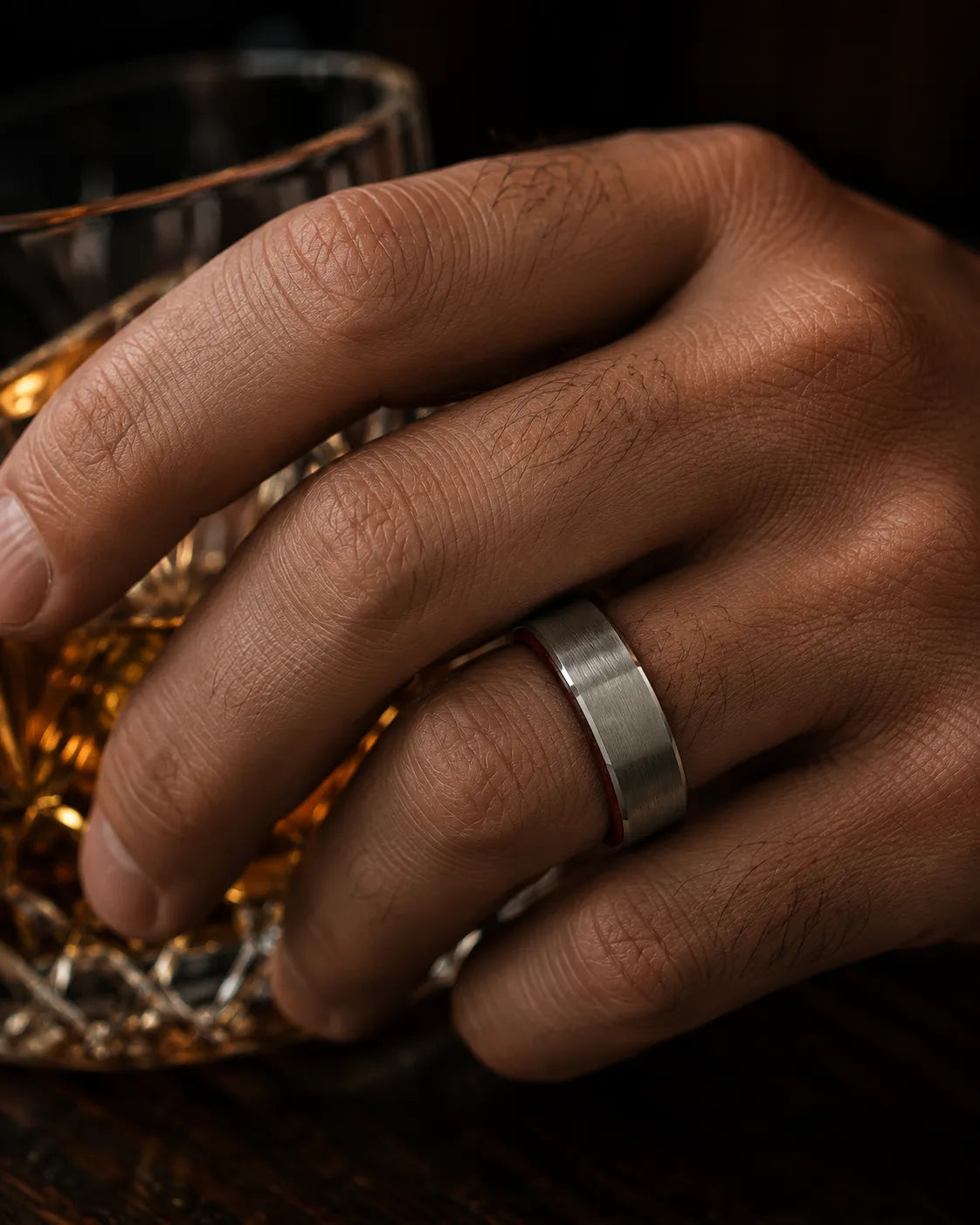 Macro close up of an 8mm brushed silver tungsten wedding ring with polished edges and maple wood sleeve on a man's hand