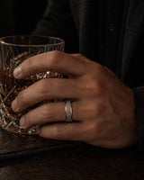 8mm rose gold meteorite inlay tungsten wedding ring worn by a man holding a crystal whiskey glass