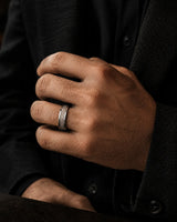 8mm silver meteorite inlay tungsten wedding ring worn by a man holding a crystal whiskey glass