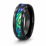 Angled view of a faceted black tungsten wedding ring with a genuine abalone shell inlay on a white background.