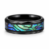 Faceted black tungsten wedding ring with a genuine abalone shell inlay lying flat on a white background.