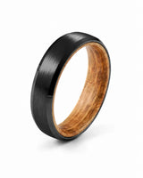 Black beveled tungsten wedding ring with whiskey barrel wood inner sleeve shown at a 35 degree angle on a white background.