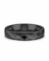 Black faceted tungsten wedding ring lying flat, showing the diamond-cut finish
