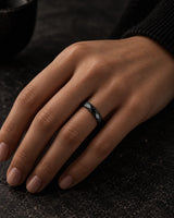 Woman wearing a black 4mm faceted tungsten wedding ring on her ring finger