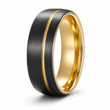 Angled view of a brushed black tungsten wedding ring with an asymmetric gold groove and polished gold interior on a white background.