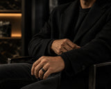 Man wearing a black groove tungsten wedding ring in a dark cinematic lifestyle setting with premium masculine styling.