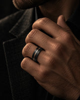 Man wearing a brushed black wedding ring with a rose gold offset groove.