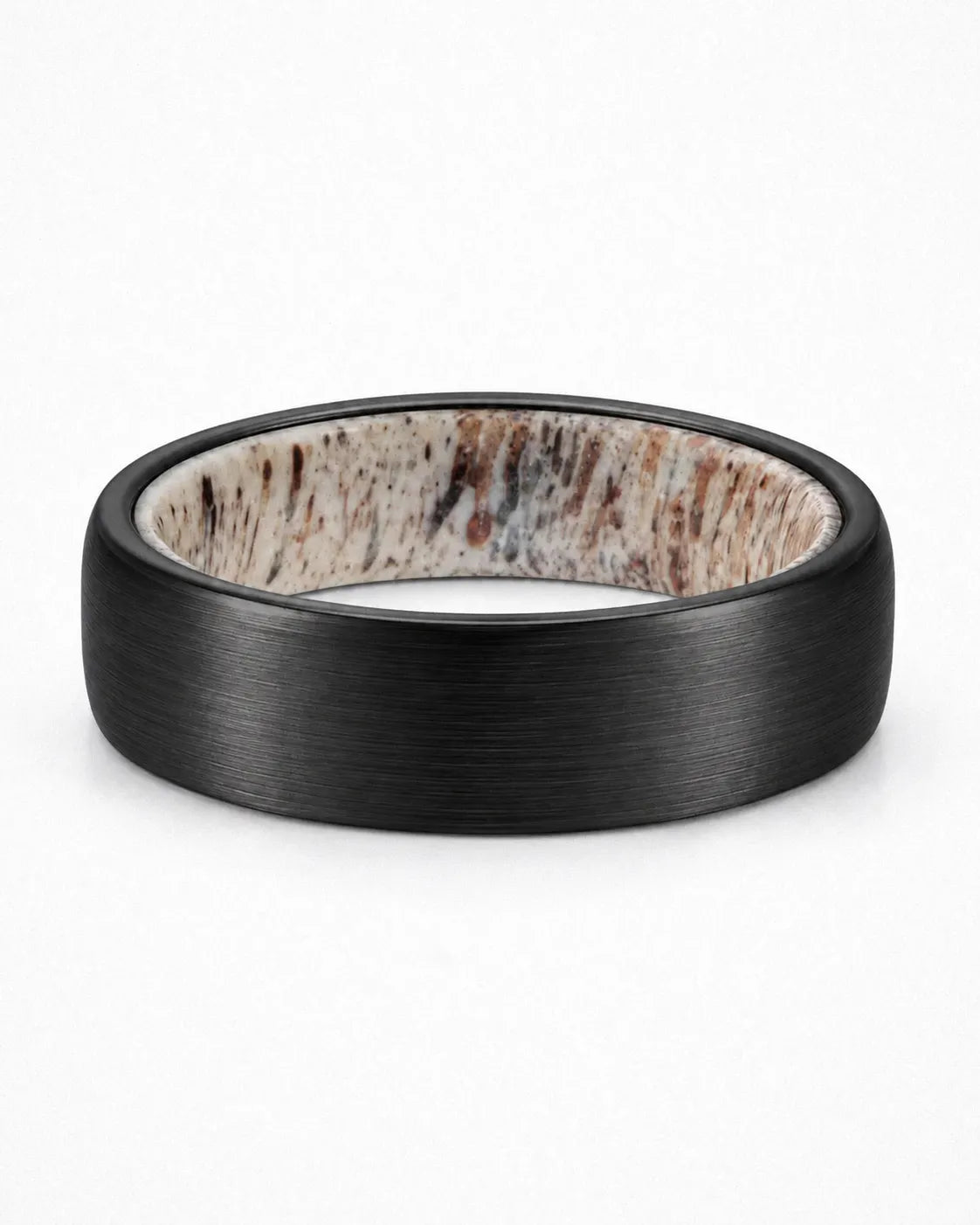 Brushed black tungsten wedding ring lying flat showing natural antler inner sleeve