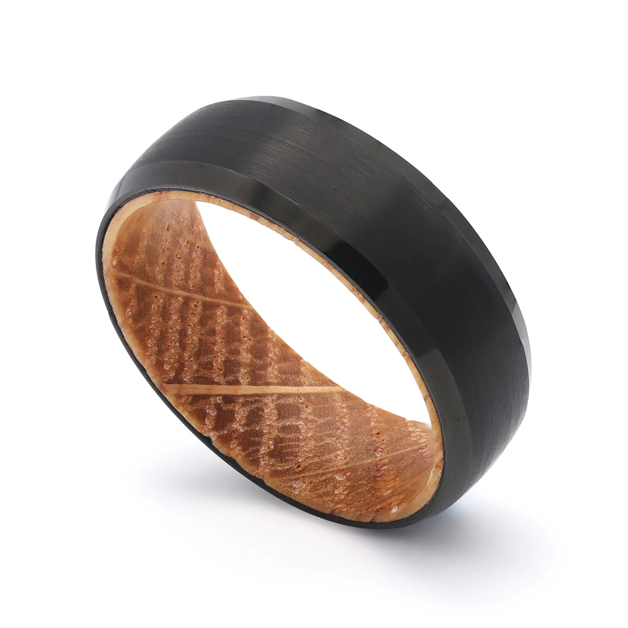 Angled close-up of a black beveled tungsten wedding ring with a real whiskey barrel oak wood interior.