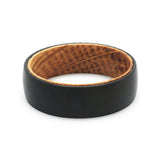 Top view of a black tungsten wedding ring with a real oak whiskey barrel wood interior.