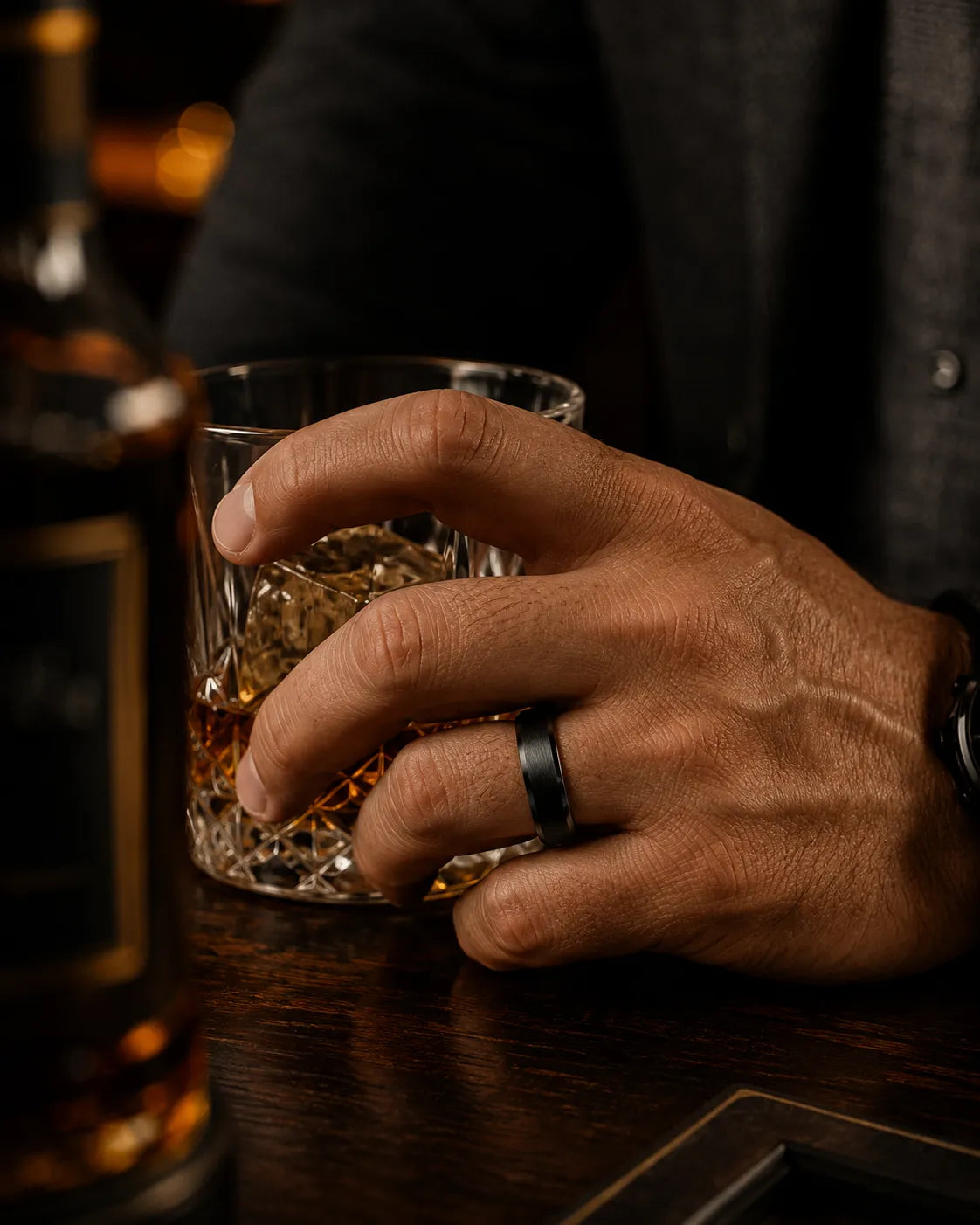 Man wearing a black brushed tungsten wedding ring with polished beveled edges and a whiskey barrel wood interior while adjusting a charcoal jacket.