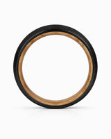 Side profile of a black tungsten wedding ring showing the band thickness, brushed finish and whiskey wood interior on a white background.