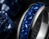 Ultra close-up macro photograph showing the detailed blue sapphire gemstone inlay and polished silver tungsten edges of a luxury wedding ring.