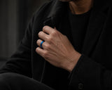 Man wearing a blue tungsten wedding ring with modern dark luxury styling in a cinematic urban setting