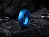 Blue tungsten men’s wedding ring resting on dark volcanic rock with moody cinematic lighting and rugged charcoal textures
