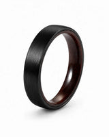 Brushed black tungsten wedding ring with a maple wood sleeve interior shown at an angled view on a white background.