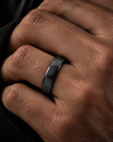 Man wearing a polished black tungsten wedding band while adjusting his dark jacket, showing the smooth rounded profile and reflective finish.