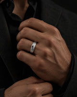 Man wearing a polished silver tungsten wedding ring with a rounded court profile while adjusting a dark tailored jacket.