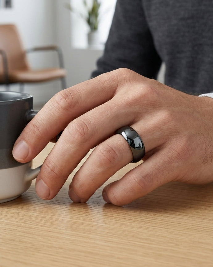 Person's hand with a ring holding a mug on a wooden table