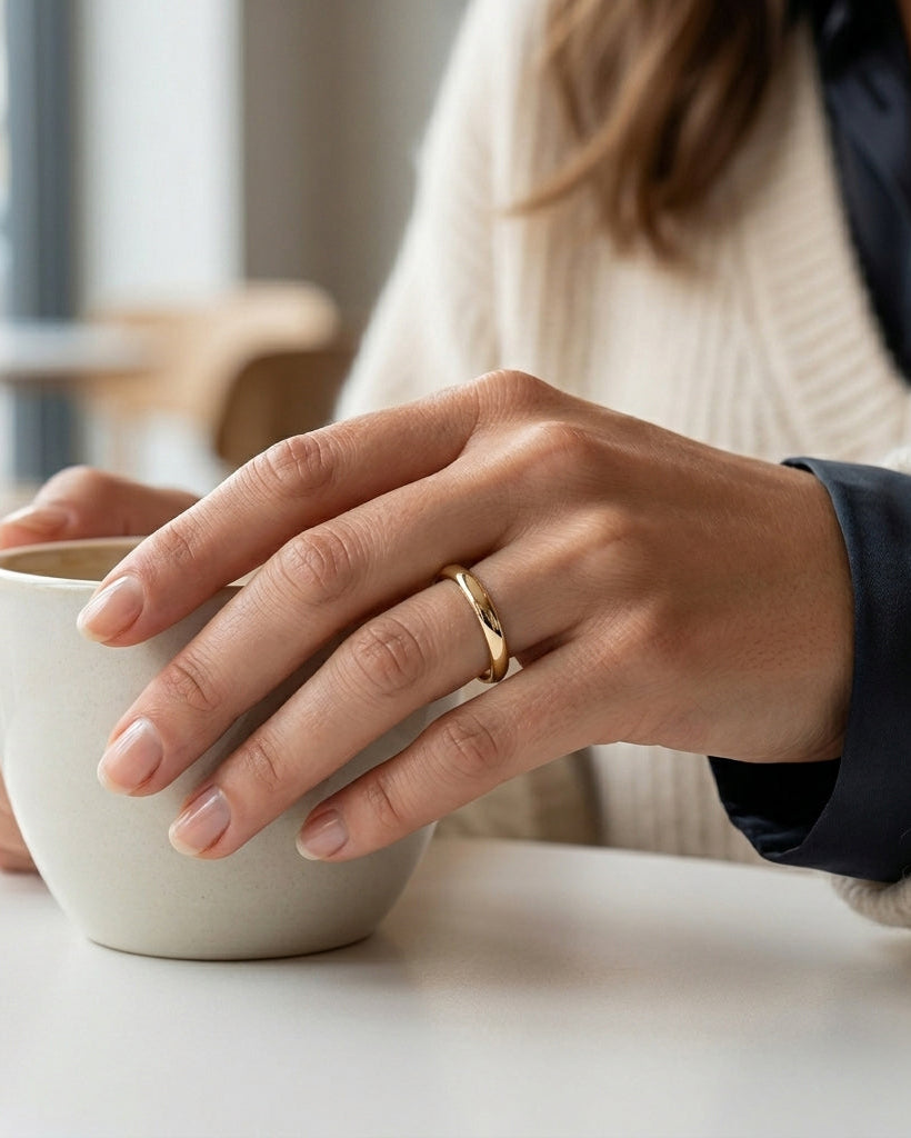 woman wearing a polished gold tungsten ring whilst holding a coffee cup