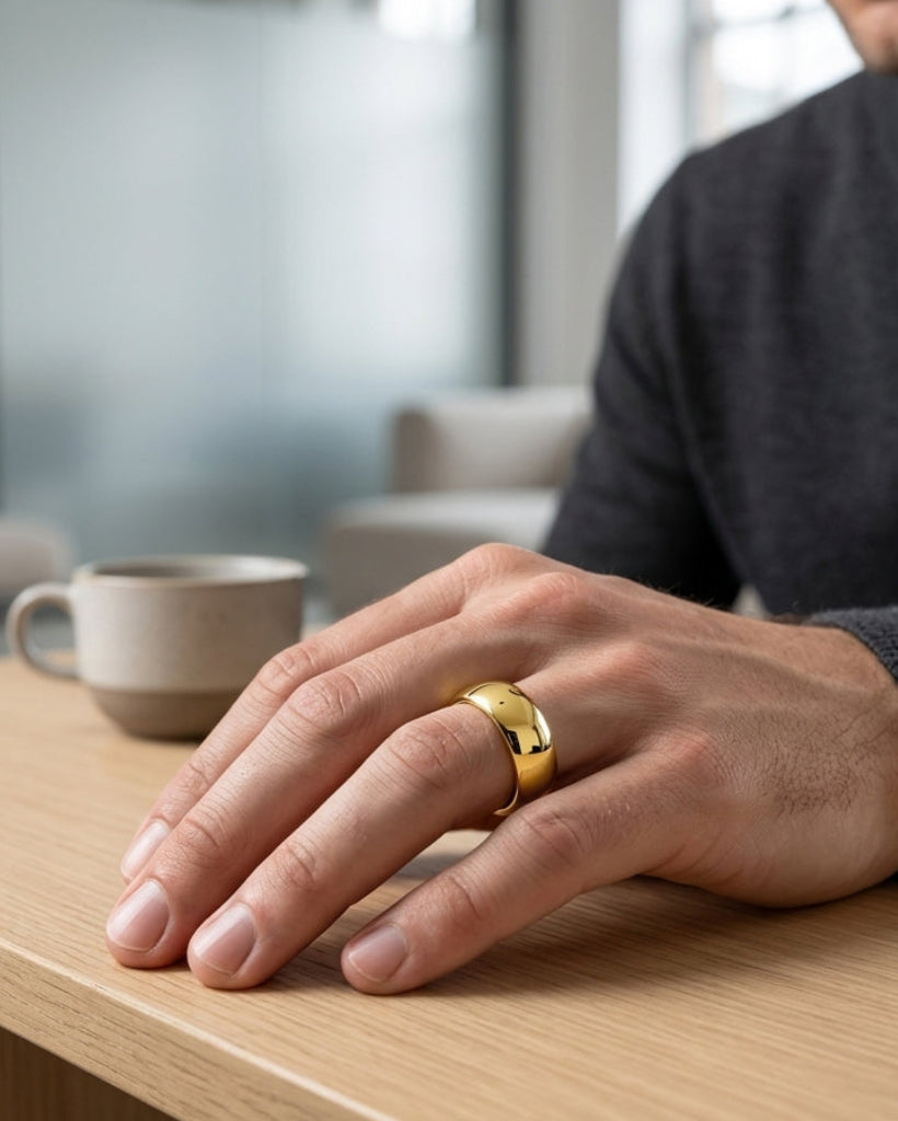 Man wearing a gold ring on a wooden table with a blurred background