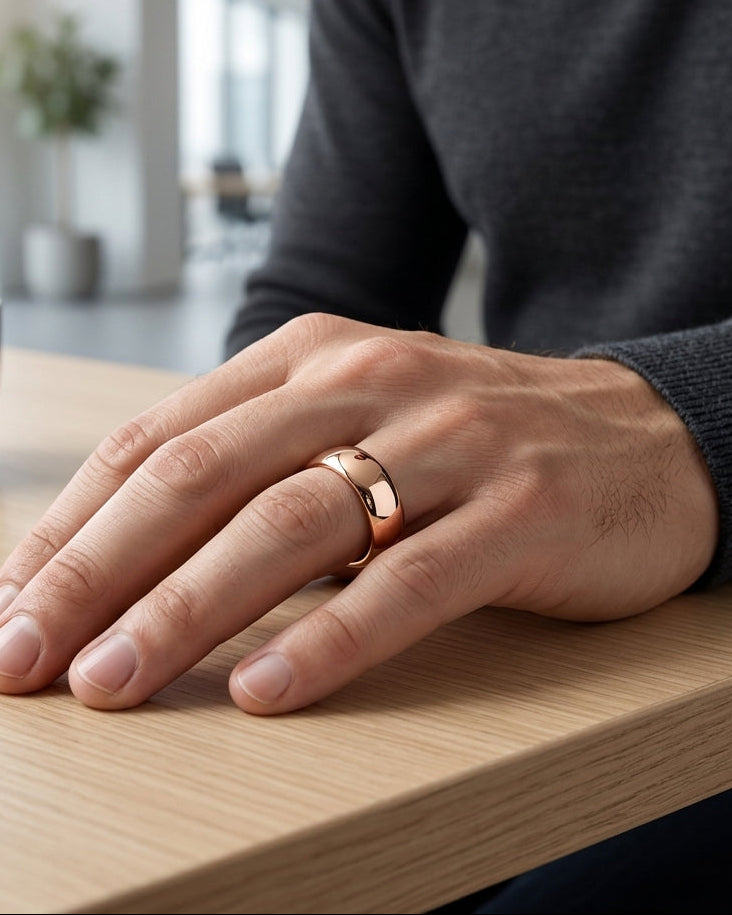 Hand wearing a rose gold ring on a wooden table with a blurred indoor background