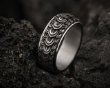 Ultra close-up macro photograph of a silver dragon scale wedding ring resting on volcanic rock with detailed texture and cinematic lighting.