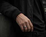 Man wearing a silver dragon scale textured wedding ring with dark luxury styling and moody cinematic lifestyle photography.