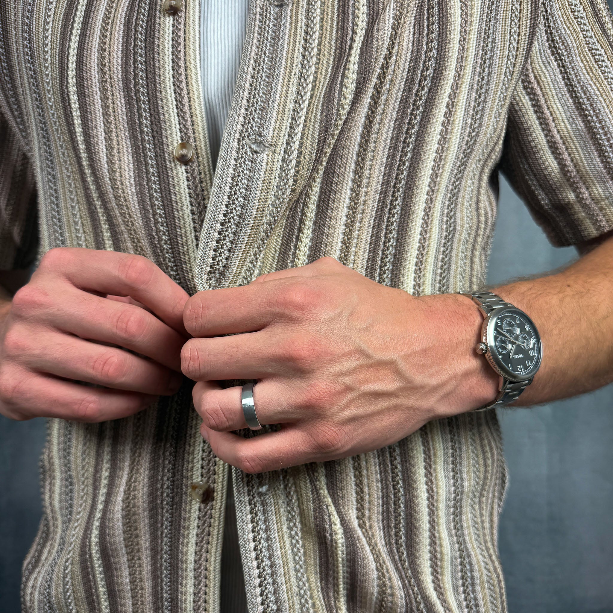 man wearing a brushed silver tungsten wedding ring doing his shirt button up