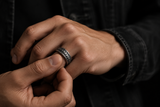 Man spinning a silver dragon scale fidget ring on his finger in a moody lifestyle close-up.