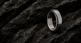 Fidget ring collection hero image featuring a silver stainless steel spinner ring on dark textured rock with cinematic lighting.