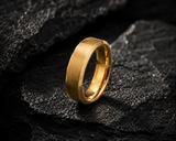 Gold men’s wedding ring on dark volcanic slate with moody cinematic lighting and luxury masculine jewellery styling