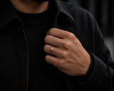 Man wearing a brushed gold wedding ring with dark modern outfit and premium urban lifestyle aesthetic