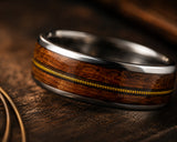 Ultra close-up macro photo of silver guitar string wedding ring showing reclaimed wood grain and detailed guitar string inlay