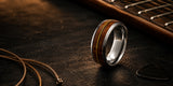 Luxury desktop hero image of silver guitar string wedding ring with reclaimed wood inlay on dark rustic wood background