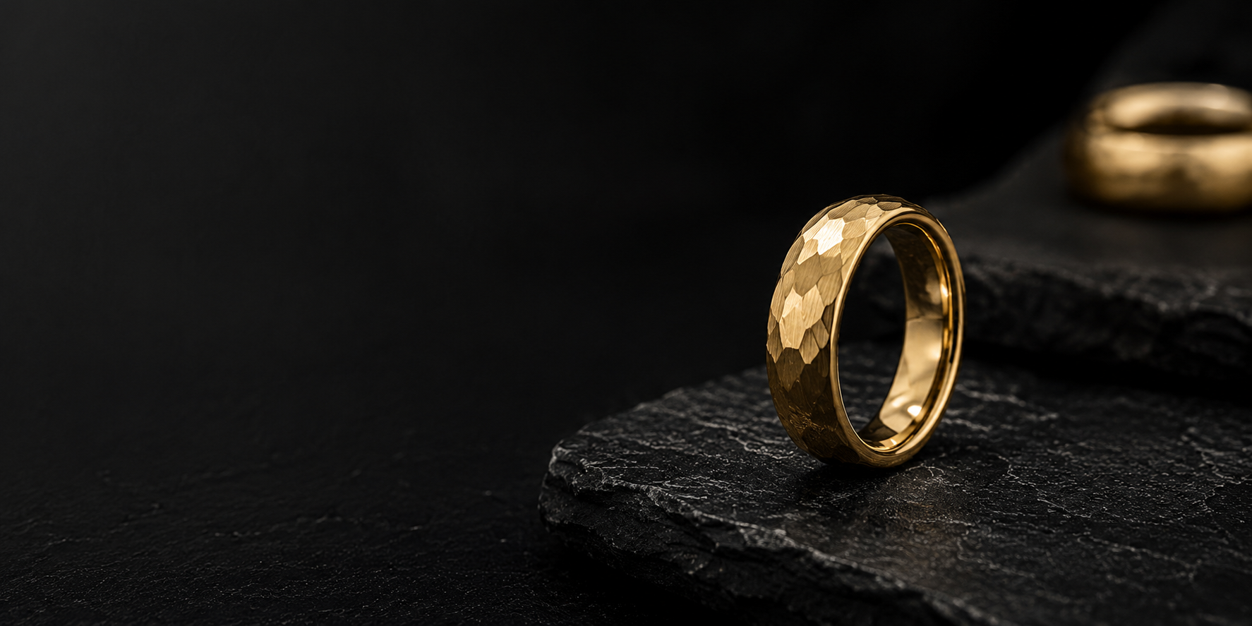 Hammered gold men’s wedding ring on dark slate stone with moody cinematic lighting and premium luxury ecommerce styling