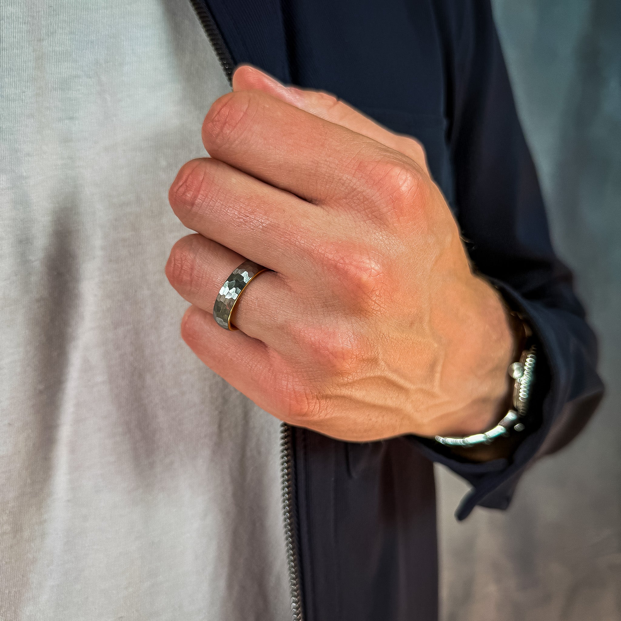 Hand wearing a silver ring with a blurred background